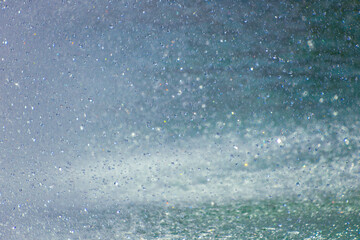 Water spray and droplets in sunlight creating a rainbow effect