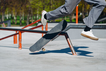 modern skate park, young boy with skateboard slides on metal pipe and falls in city skate park in...
