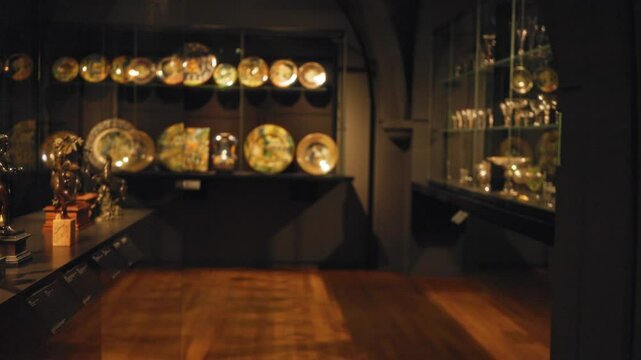 Art gallery with blurred focus showcasing decorative plates and sculptures under soft lighting indoors.