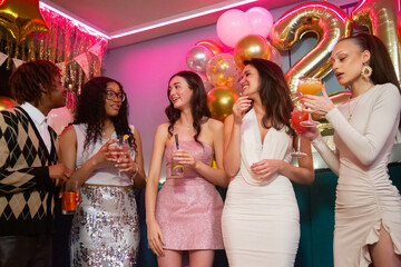 Group of female friends standing with cocktails during birthday party