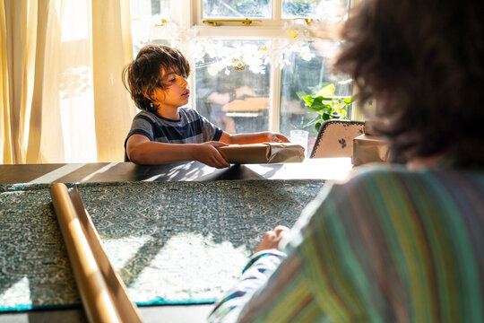Young men with little sister preparing gifts for Eid Celebration