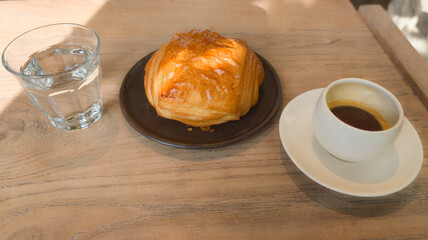 chocolate bread french croissants and a cup of coffee on table home interior in lifestyle with water glass