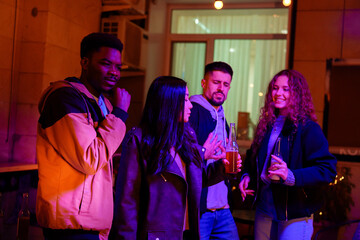 Friends enjoying a lively evening at a vibrant outdoor gathering in the city, sharing laughter and drinks under colorful lights