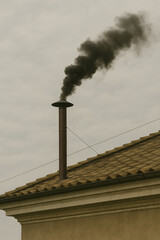 Smoke Rises From a Chimney on a Cloudy Day in a Rural Setting