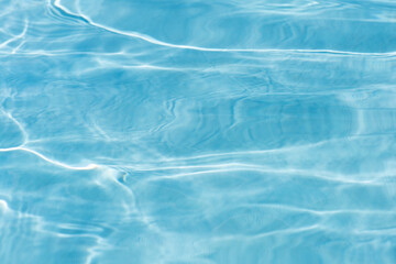 Blue water with ripples on the surface. Defocus blurred transparent blue colored clear calm water surface texture with splashes and bubbles. Water waves with shining pattern texture background.