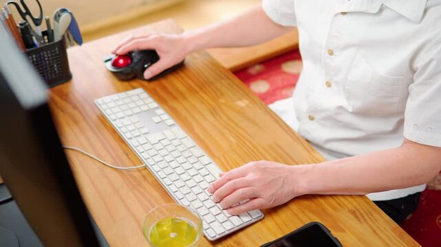 マウスを操作した後キーボードを使って入力作業をする男性