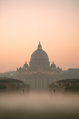 Obraz premium Majestic View of St. Peter's Basilica Shrouded in Morning Mist Under a Soft Pastel Sky at Dawn