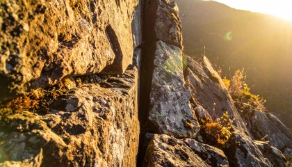 Rocky cliff with a narrow crack bathed in golden sunlight, blurry background