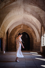 Obraz premium Woman in Floral Dress Walking Through Gothic Stone Corridor