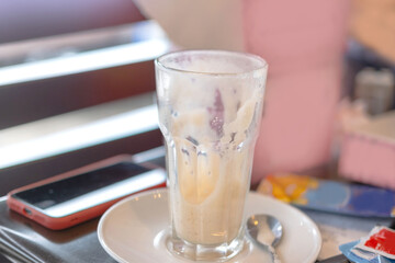 Evidence of a completed break or casual dining moment, Glass with drink remnants on saucer, casual cafe setting, finished beverage