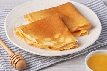 Traditional Russian pancakes with honey on a white wooden table