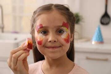 Animator drawing butterfly on girl's face indoors, closeup