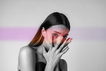 Fototapeta premium Portrait of a woman expressing emotion with hands covering her face in a minimalist setting during daylight