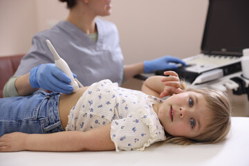 Sonographer conducting little girl's abdominal ultrasound examination in clinic, closeup