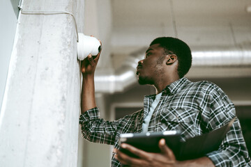 Technician installs security camera in modern office building during daylight hours