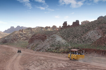 SUV car and quad bike moving on dusty road at Pingshan Hu Grand Canyon in summer, Zhangye City, Gansu Province in China