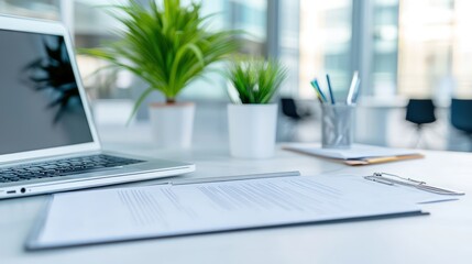 Laptop and documents on desk in bright office environment for business finance work