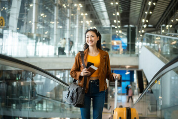 happy young asian woman traveler holding boarding pass ticket, passport and smartphone at the...