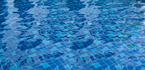 Blue swimming pool water, with waves, and reflections from sunlight