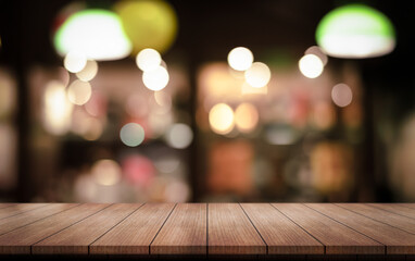 Empty wooden table top with lights bokeh on blur restaurant background.