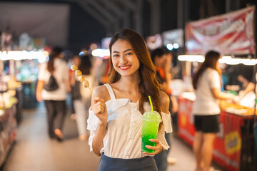 Asian woman enjoy eating noodles street food at night market. Traveler Asian blogger women Happy tourists Beautiful female with Traditional thailand bangkok food.