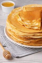 Traditional Russian pancakes with honey on a white wooden table. Homemade russian thin pancakes blini. Russian food, russian kitchen