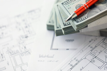 Big amount of US dollars money bills with pen and planning blueprints of residential building project close up. Investment and construction project concept