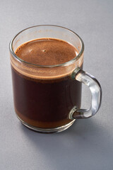 A glass of brewed coffee with grey background