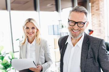 Two professional colleagues in formal business attire working together in a modern office setting...