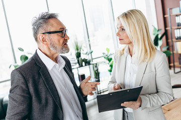 Obraz premium Professional colleagues discussing project details in modern office during a collaborative meeting showcasing teamwork