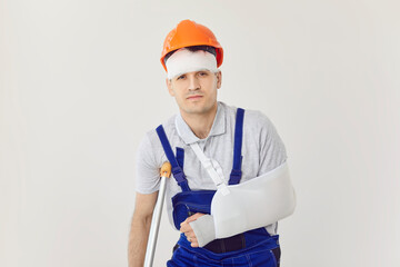 Accident and injury during construction works. Portrait of builder with injured head, arm and leg....