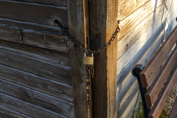 Close-up of rusty chain and padlock on wooden shed corner in sunset light. Mediterranean, Turkey.