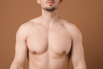 Fototapeta premium Young man with smooth chest after epilation procedure on brown background, closeup