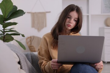 Cyber bullying. Upset teenage girl with laptop on sofa at home