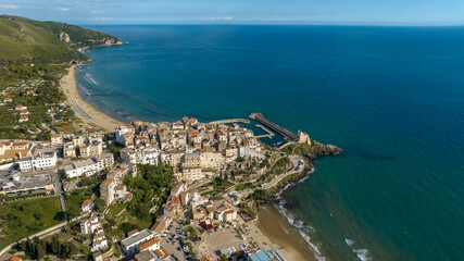 Fototapeta premium Aerial view of the town of Sperlonga, in the province of Latina, Lazio, Italy. The village is built on a promontory overlooking the Mediterranean Sea. In the background is the city beach.