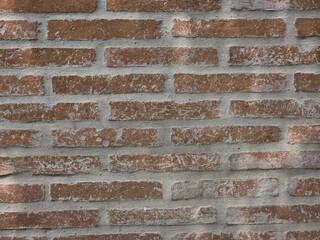 Textured brick wall with rustic appearance, featuring mix of red and gray tones, ideal for backgrounds or architectural designs