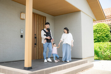 玄関のドアから出る4人家族のお出かけシーンのいってきますイメージ　