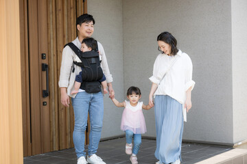 玄関のドアから出る4人家族のお出かけシーンのいってきますイメージ　