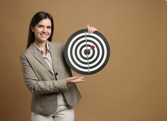 Targeting. Smiling businesswoman with dart board and arrow on beige background. Space for text
