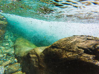 Crystal clear water of a Norwegian mountain river: an amazing underwater view of stones, bubbles,...