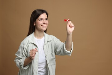 Targeting. Smiling woman with dart aiming on beige background
