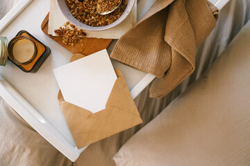 Top view of a cozy breakfast tray with granola and banana bowl, glass bottle of milk, jar candle,...