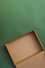 Empty brown cardboard gift box placed on a solid green background. Eco-friendly packaging concept with minimalist, natural aesthetic and copy space