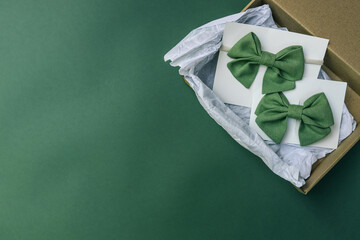 Eco-friendly packaging with two green fabric hair bows on white cards placed inside a brown kraft...