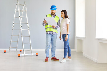 Man construction industry engineer and builder in uniform and hardhat and young woman homeowner talk about home remodeling, discuss house renovation, and develop indoor living space redesign project
