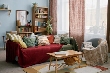 Interior of bright and inviting living room with comfortable couch adorned with colorful throw...