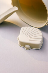 Beige silicone beach toys including bucket, scoop, and shell mold on neutral background with soft shadows