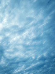 Serene sky filled with soft fluffy clouds. Calm atmosphere blue vertical background. Soft light and gentle textures evoke a sense of peaceful.