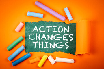 ACTION CHANGES THINGS Concept with Torn Paper and Colorful Chalk on Orange Background