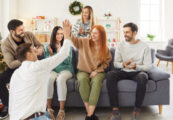 Group of happy friends gives high fives during a celebration party at home. The diverse crowd...